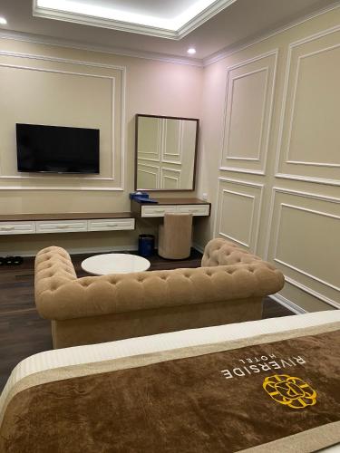 a living room with a couch and a tv at Riverside Hotel Hà Nam in Phủ Lý