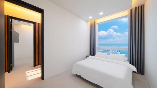 a bedroom with a white bed and a large window at Milos Pool Villa - K102 in Yeosu