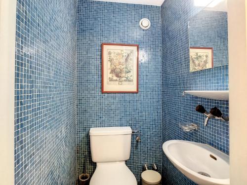 a blue tiled bathroom with a toilet and a sink at Séracs 35*** in Verbier
