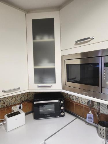 a kitchen with white cabinets and a microwave at La casa sobre el rÍo in Cuenca