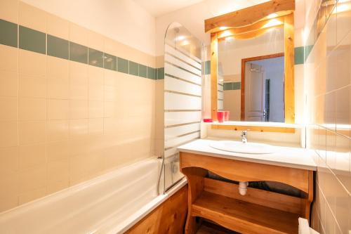 une salle de bain avec un lavabo, une baignoire et un miroir dans l'établissement Le Silène - Appt pour 6, à Chamrousse