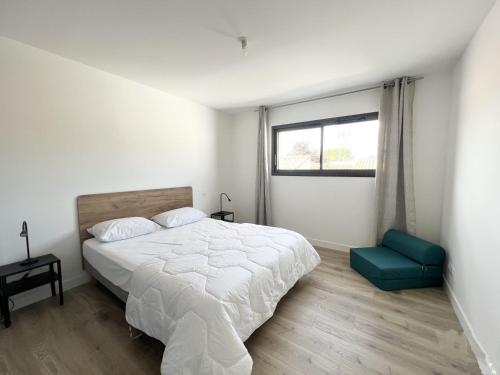 a bedroom with a white bed and a blue chair at Le Clos Guiton in La Rochelle