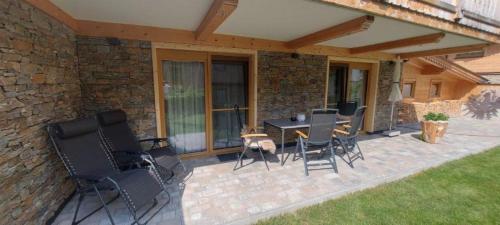 a patio with chairs and a table on a brick wall at Chalet Leßner in Leutasch