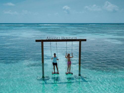 two people on a swing in the ocean at Araamu Holidays & Spa in Dhiffushi