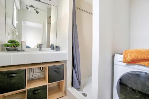 a bathroom with a sink and a washing machine at Expédition Malouine - Appt à 30m de la plage in Saint Malo