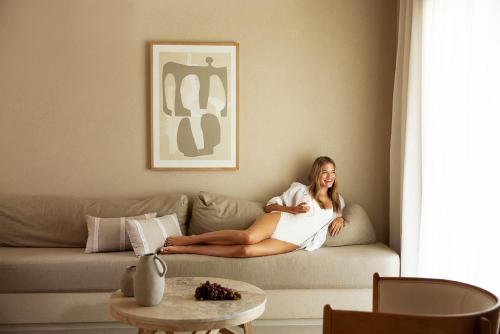 a woman sitting on a couch in a living room at Domes Noruz Mykonos in Mýkonos City