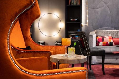 a living room with orange chairs and a table with a drink at Design Hotel f6 in Geneva