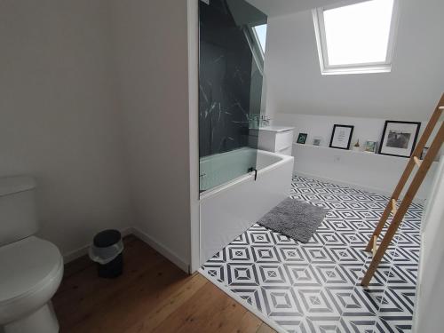 a bathroom with a toilet and a television on a floor at Le Nid Normand avec Terrasse - Stationnement facile et Gratuit - 5 min Seine in Déville-lès-Rouen