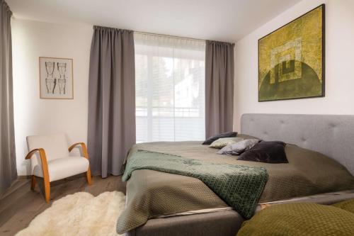 um quarto com uma cama, uma cadeira e uma janela em Apartmanica Triangel 222 em Donovaly
