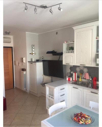 una cucina con armadi bianchi e un piatto su un tavolo di delizioso appartamento a San Benedetto del Tronto