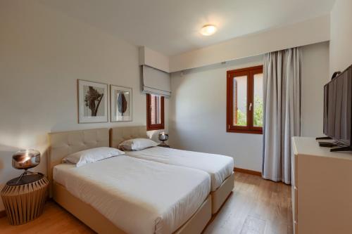 a bedroom with two beds and a television at Aphrodite Hills Rentals - Mythos Collection Villas in Kouklia