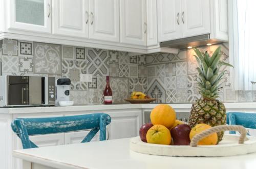 a white kitchen with a bowl of fruit on a counter at Sea & Olives Suites Hotel and Villas in Plaka