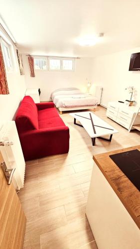 a living room with a red couch and a table at STUDIOS La Varenne Saint Maur entre PARIS ET DISNEYLAND in Saint-Maur-des-Fossés