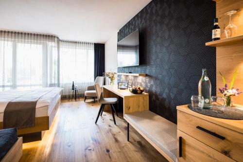 a bedroom with a bed and a desk in a room at Wirthshof Hotel & Chalets in Markdorf