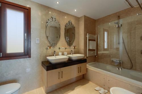 a bathroom with two sinks and a tub and mirrors at Aphrodite Hills Rentals - Mythos Collection Villas in Kouklia