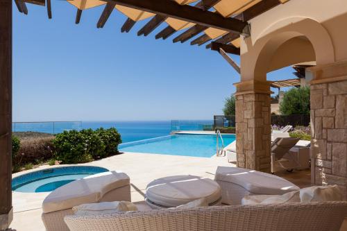 a patio with chairs and a swimming pool at Aphrodite Hills Rentals - Mythos Collection Villas in Kouklia