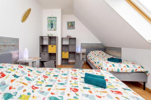 a attic bedroom with two beds and a desk at L’Albizia … Maison familiale proche des plages in Plougoulm