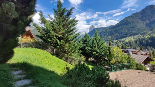 a hillside with trees and a fence and mountains at Villa Suredl in Ortisei