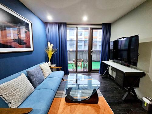 a living room with a blue couch and a flat screen tv at JS Boutique Hotel in Hwaseong