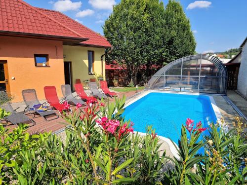 a swimming pool in a yard with chairs and flowers at Apartmány Comfort in Střílky