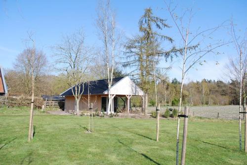 a barn in a field with trees in front of it at Vrijstaande woning Drenthe bij het bos. in Bovensmilde