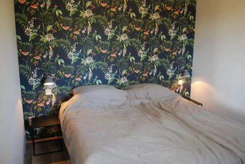 een slaapkamer met een bed met bloemenbehang bij Vrijstaande woning Drenthe bij het bos. 