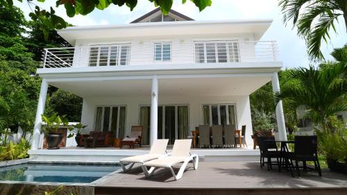 a white house with chairs and a swimming pool at Las Brisas Villa - Chateau Elysium in Beau Vallon