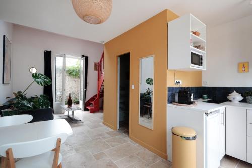 une cuisine avec des placards blancs et un mur jaune dans l'établissement La petite maison, à Neuville-aux-Bois