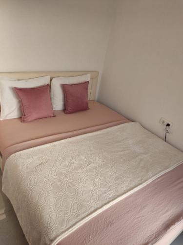 duże łóżko z biało-różowymi poduszkami w obiekcie ZLATNI LEPTIR w mieście Dobra Voda