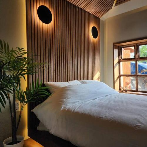 a bedroom with a white bed and a window at Peace of mind in Jeju