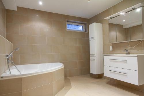 ein Badezimmer mit einer Badewanne und einem Waschbecken in der Unterkunft nidusROOMS: Suite Hockenheim in Hockenheim