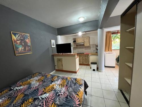 een kleine slaapkamer met een bed en een keuken bij Studio proche centre ville Papeete in Papeete
