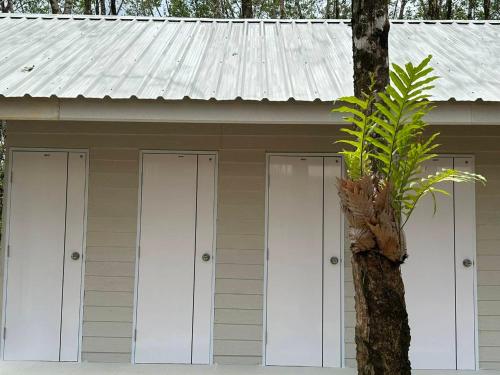 a building with four doors and a tree at Rabbit Bungalow in Ko Phayam