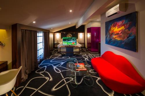 a living room with a red couch and a tv at Hôtel de Brienne in Toulouse