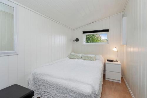 a small white bedroom with a bed and a window at Feriehus nær badeplass og Molde sentrum in Årøy