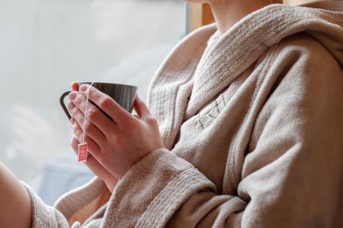 a woman in a robe holding a coffee cup at Posthotel Lechtal, Arlberg in Holzgau