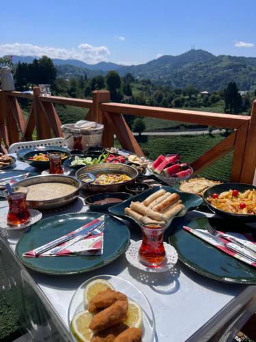 une table avec des assiettes de nourriture et des montagnes en arrière-plan dans l'établissement Green Luxury Bungalovs, à Pazar