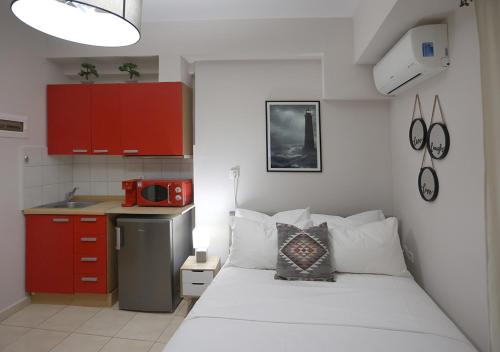 a small bedroom with a white bed and red cabinets at LD Studio Larissa in Larisa