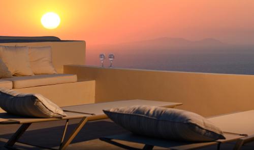 een tafel en stoelen met de zonsondergang op de achtergrond bij OIA UNIQUE HOMES by K&K in Oia