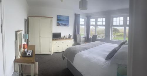 a bedroom with a bed and a desk with a television at Beacon Country House Hotel & Luxury Shepherd Huts in St. Agnes 