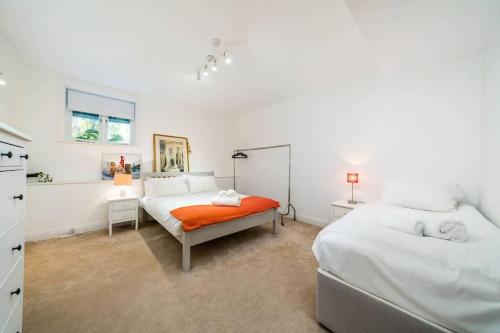 a bedroom with two beds and an orange bench at Spacious 2 bed Garden Flat by the Thames+parking in London