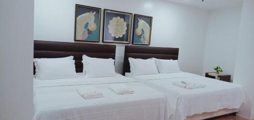 two beds in a hotel room with white sheets at TAM-AN HOTEL BANAUE in Banaue