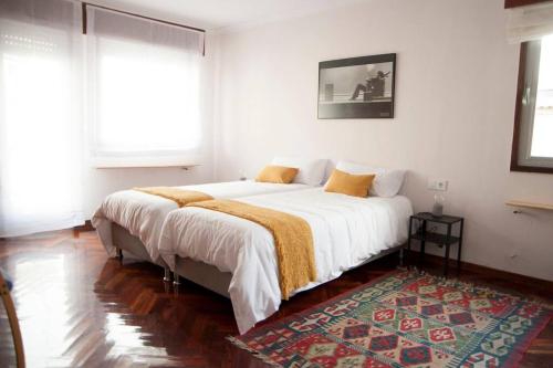 una camera da letto con un letto con lenzuola bianche e un tappeto di Casa amplia, confortable, céntrica by Prishomes a Vigo