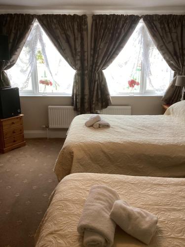 a hotel room with two beds and two windows at Barons Court in Great Yarmouth