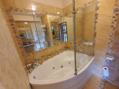 a large bathroom with a tub and a large mirror at Hotel Soccer Sport in Radomsko