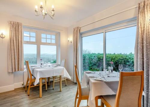 a dining room with a table and a large window at Beacon Country House Hotel & Luxury Shepherd Huts in St. Agnes 
