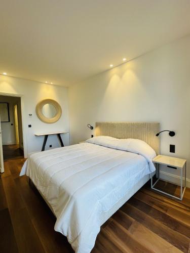 une chambre avec un grand lit blanc et un miroir dans l'établissement croisette appartement 3 chambres The Six, à Cannes