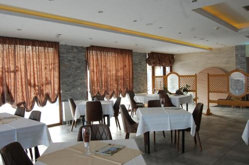 a restaurant with white tables and chairs and windows at Bački dvor in Vajska