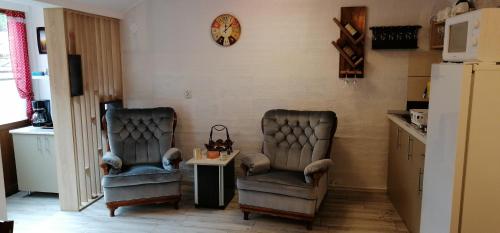 duas cadeiras numa cozinha com uma mesa e um relógio em CASA GRETA em Lupeni