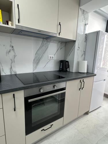 勒德烏齊的住宿－Cozy Apartment，厨房配有白色橱柜和黑炉灶烤箱。